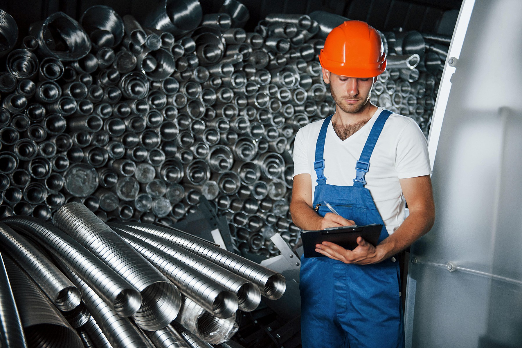 Munkavédelmi sapkát viselő férfi építőipari terméket ellenőriz ISO 9001 minősítéshez.